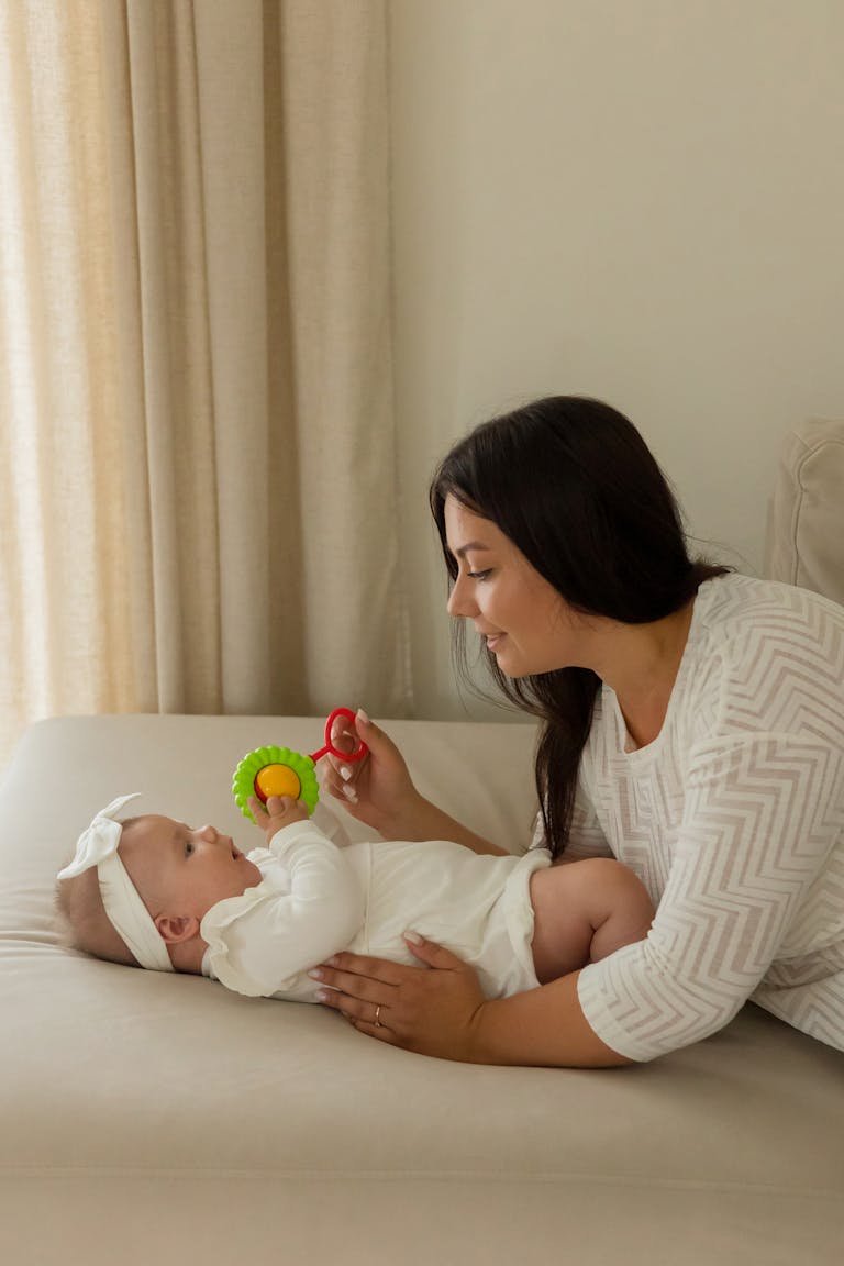 Mother playing with baby using colorful toy, fostering early development.